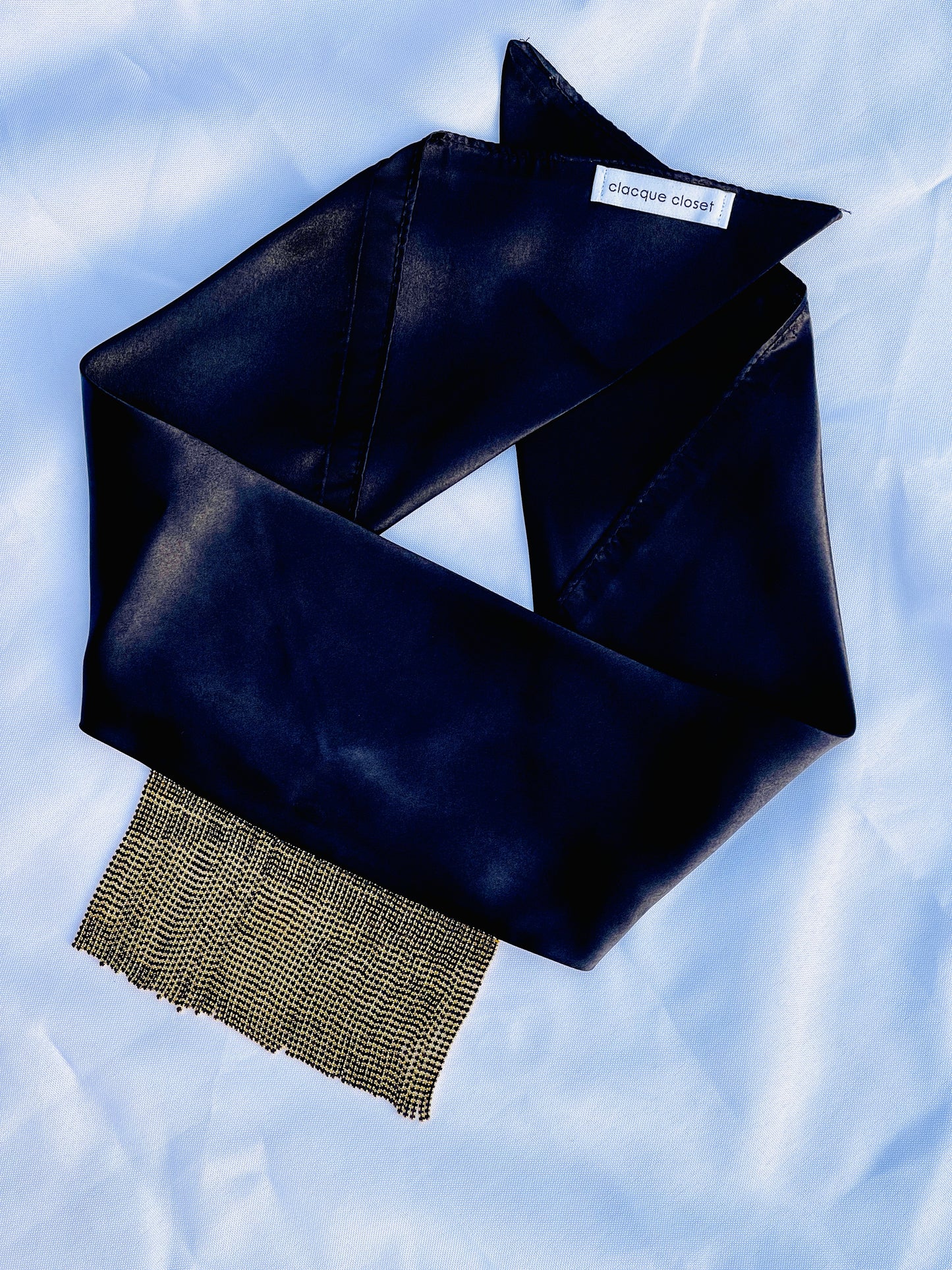 Minerva black satin bandana bang with gold fringe laid flat.