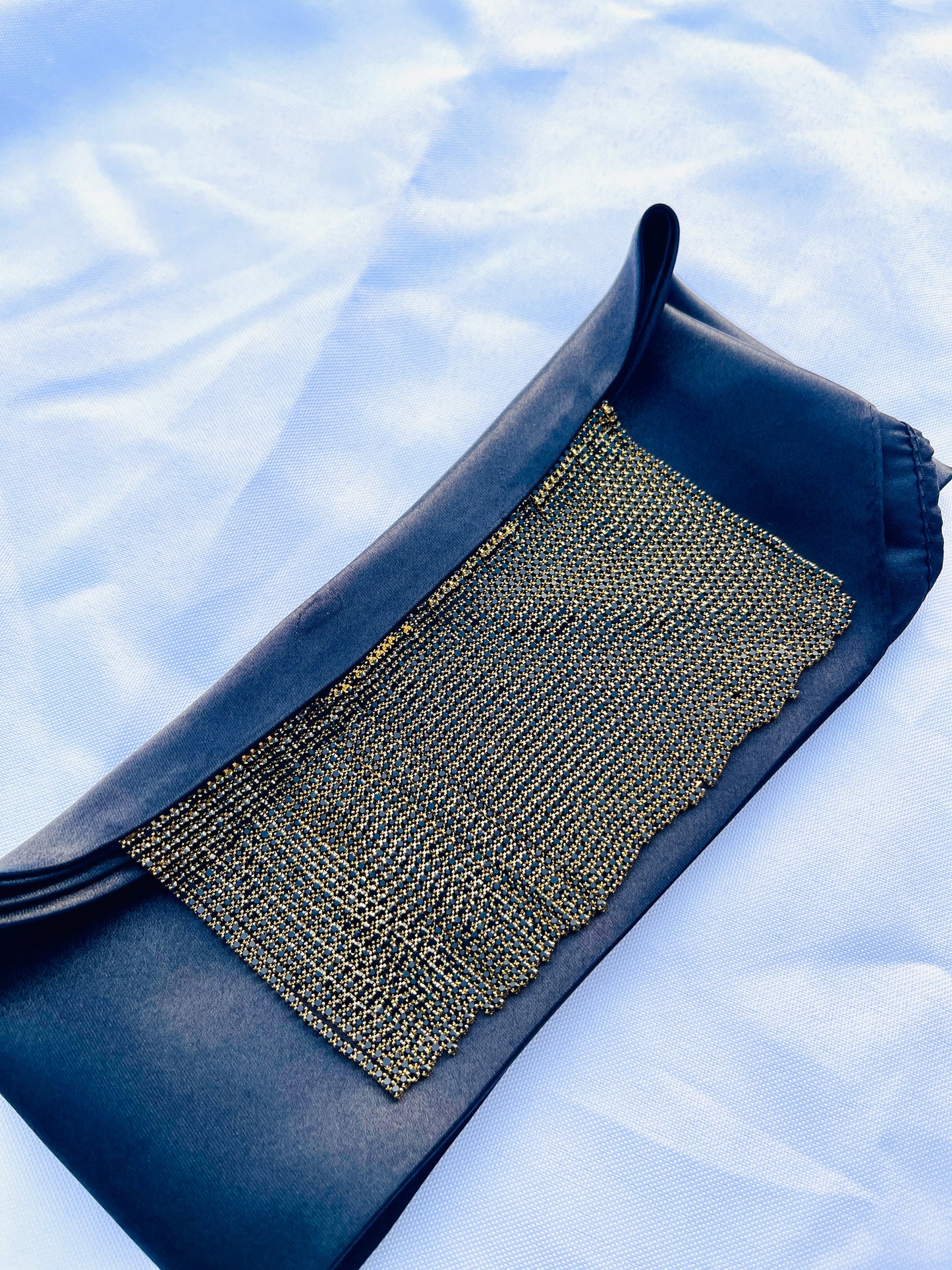 Minerva black satin bandana bang with gold fringe laid flat.
