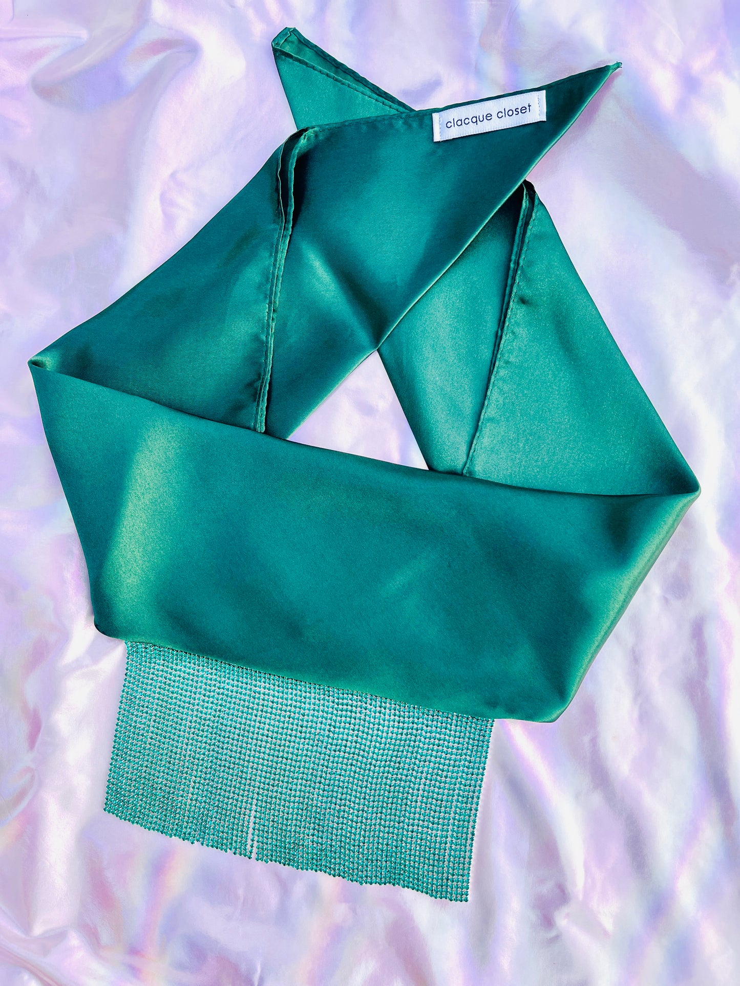 Freya handmade green satin bandana bang with turquoise fringe laid flat on iridescent background.