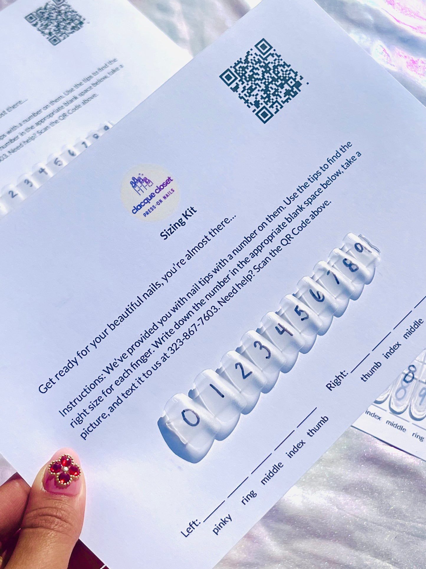 Photo of a physical nail size kit with a variety of nail tips laid out in order from smallest to largest, alongside a measuring tape for size comparison.