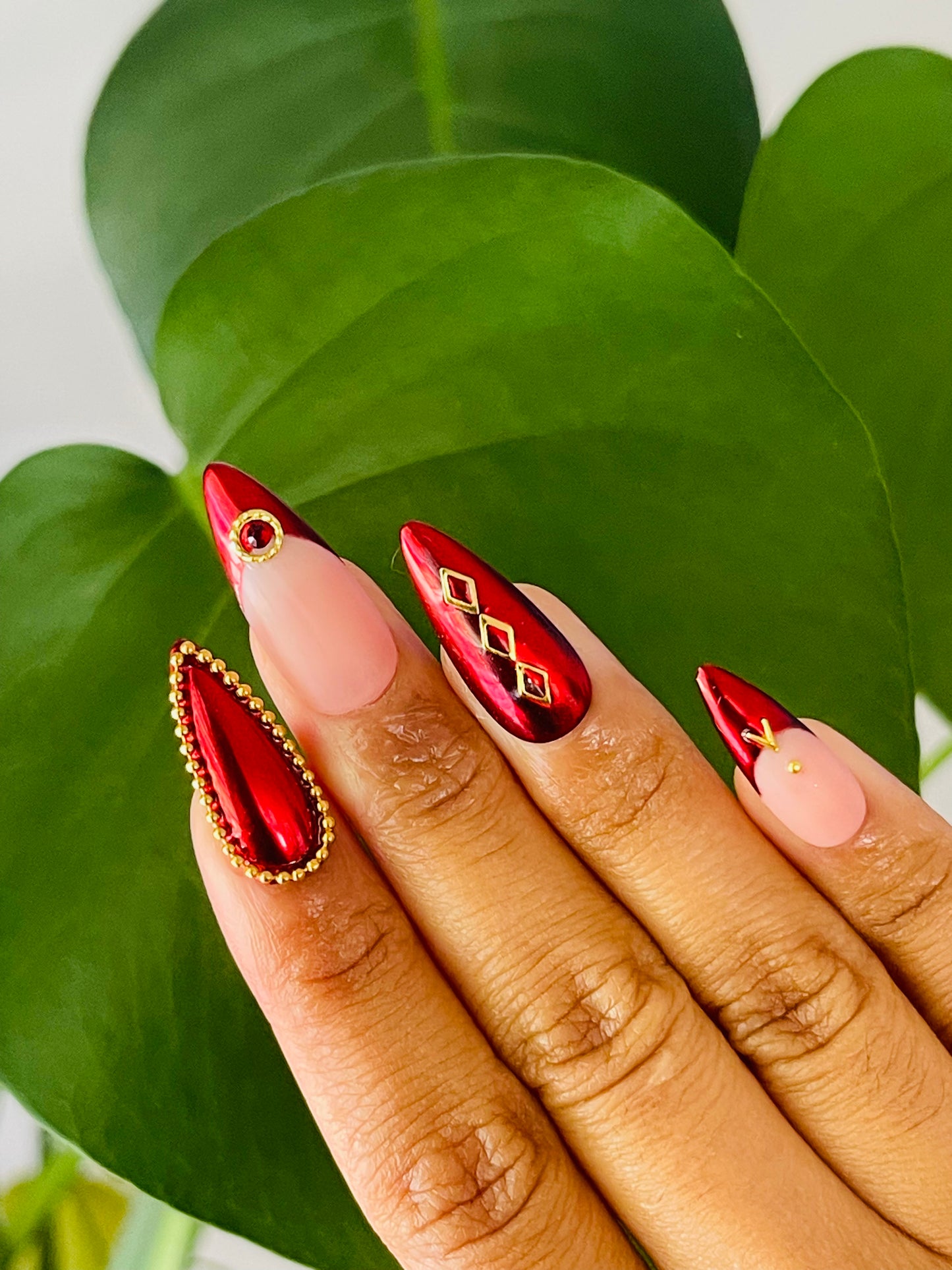 Medium-length stiletto nails featuring a classic French tip design with a modern twist, incorporating red chrome and gold accents for a striking and luxurious look.