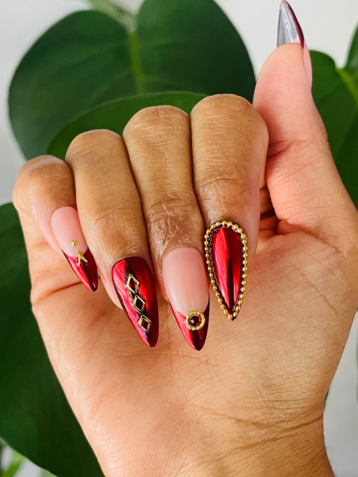 Medium-length stiletto nails featuring a classic French tip design with a modern twist, incorporating red chrome and gold accents for a striking and luxurious look.