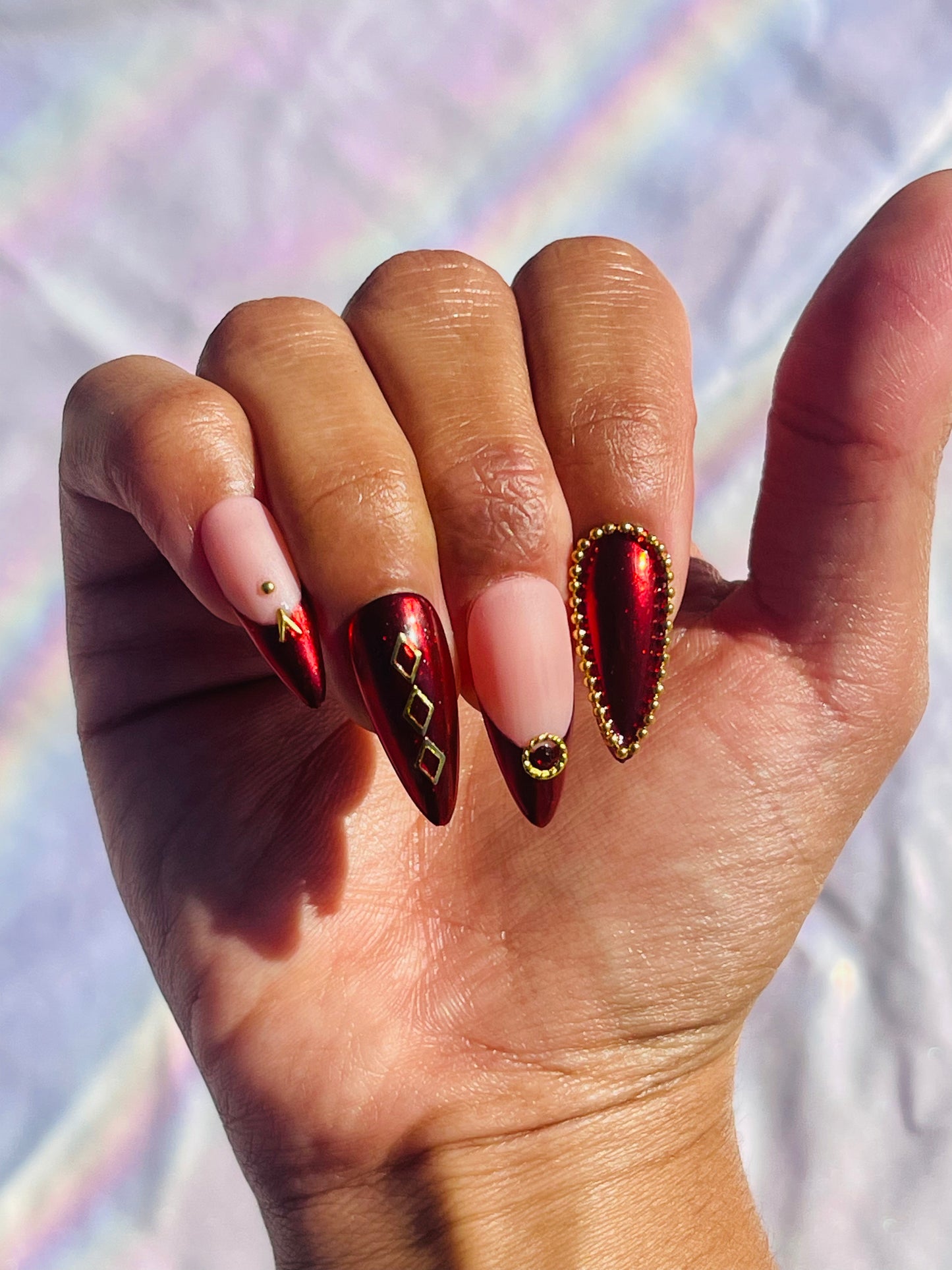 Medium-length stiletto nails featuring a classic French tip design with a modern twist, incorporating red chrome and gold accents for a striking and luxurious look.