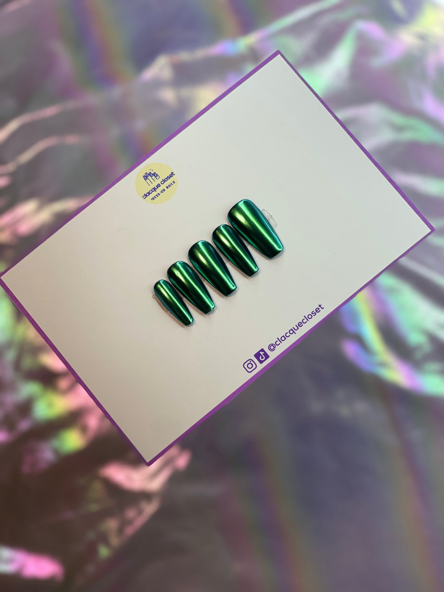 A set of press-on nails with a rich green chrome finish, exuding a bold and shimmering appearance that changes hues in varying lights.