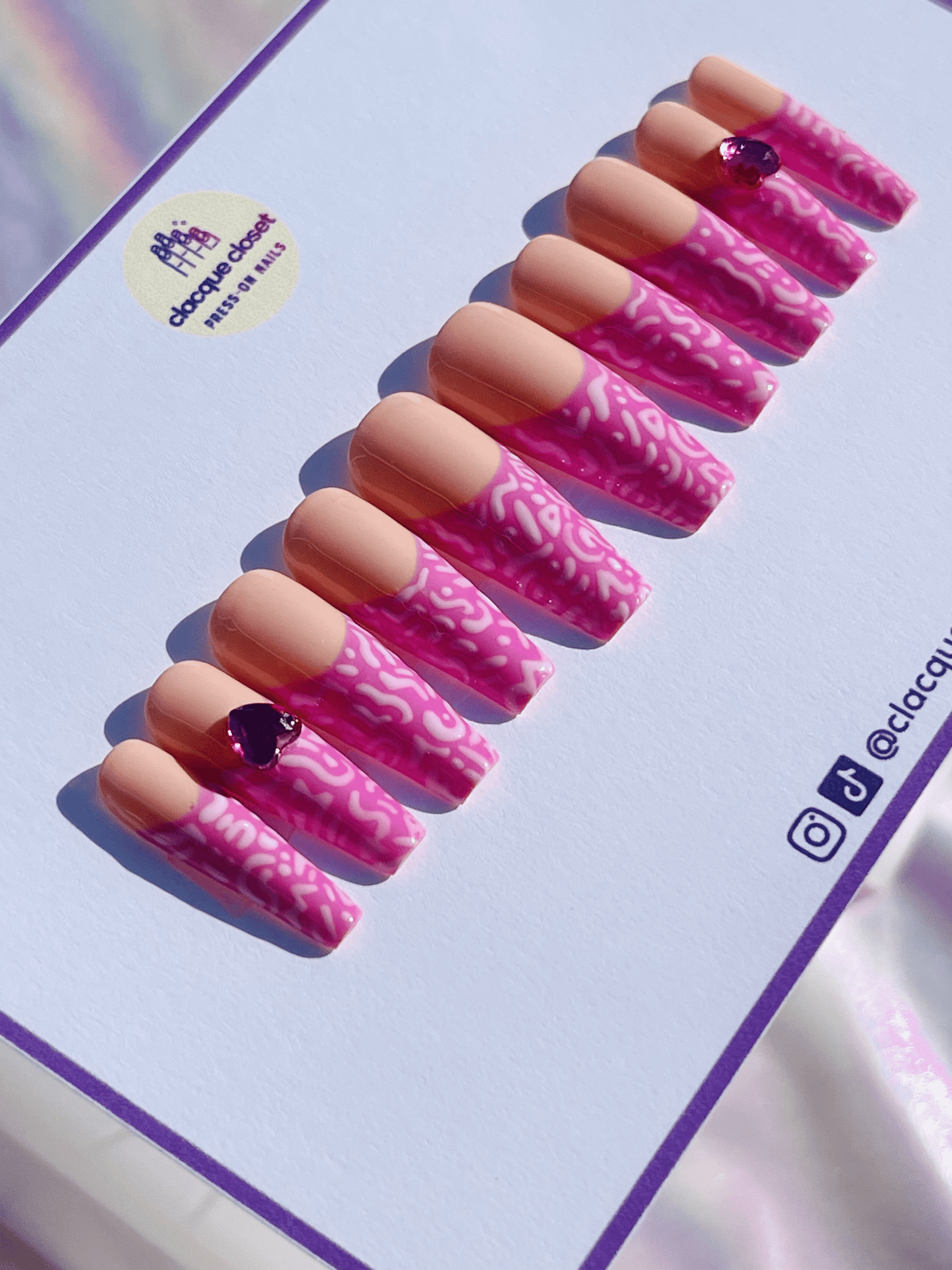 Press-on nails featuring pink line art with rhinestone hearts, adding a touch of sparkle and elegance.