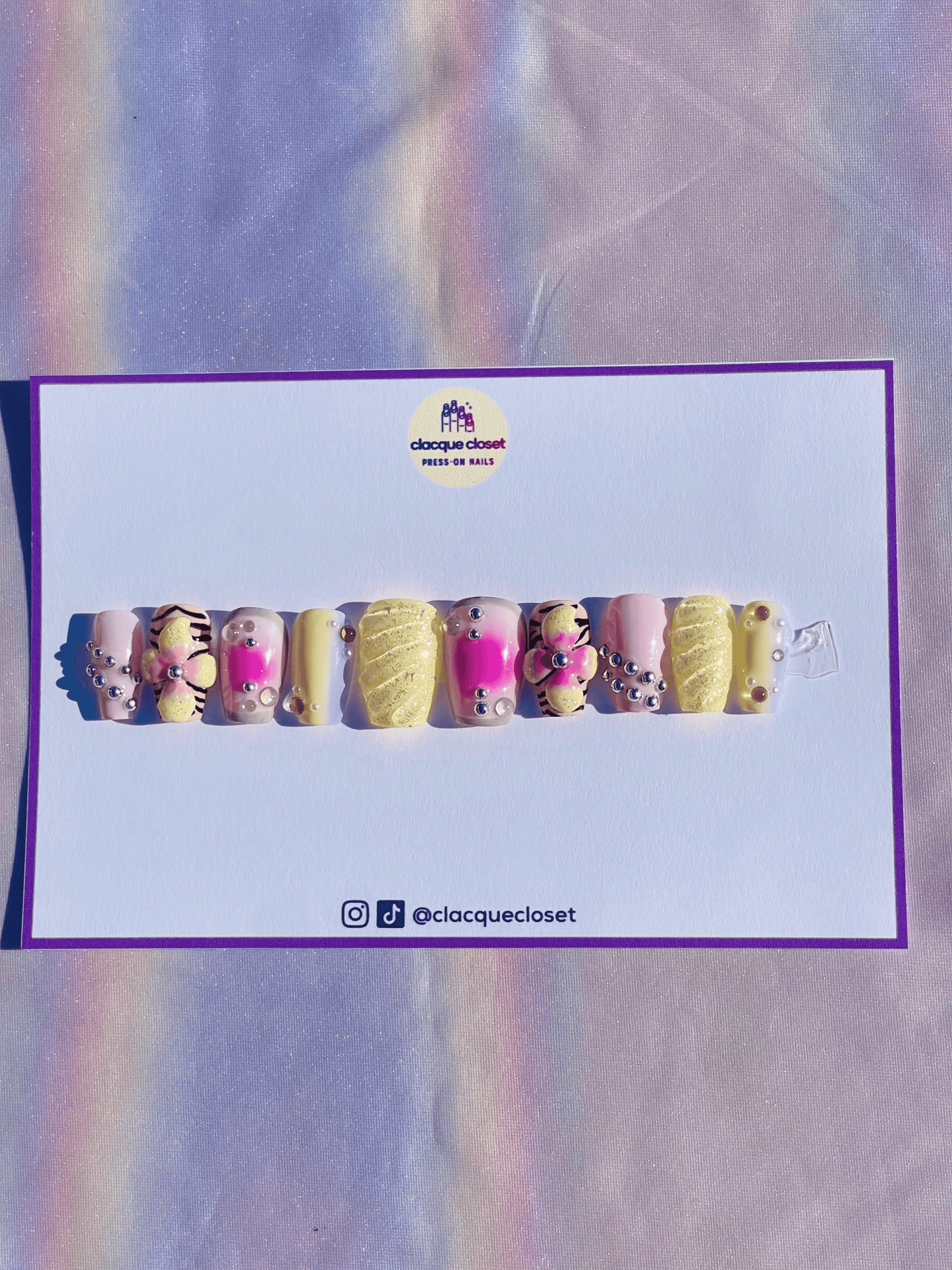 Press-on nails in pastel colors adorned with 3D flowers and charms, creating a delicate and whimsical design.