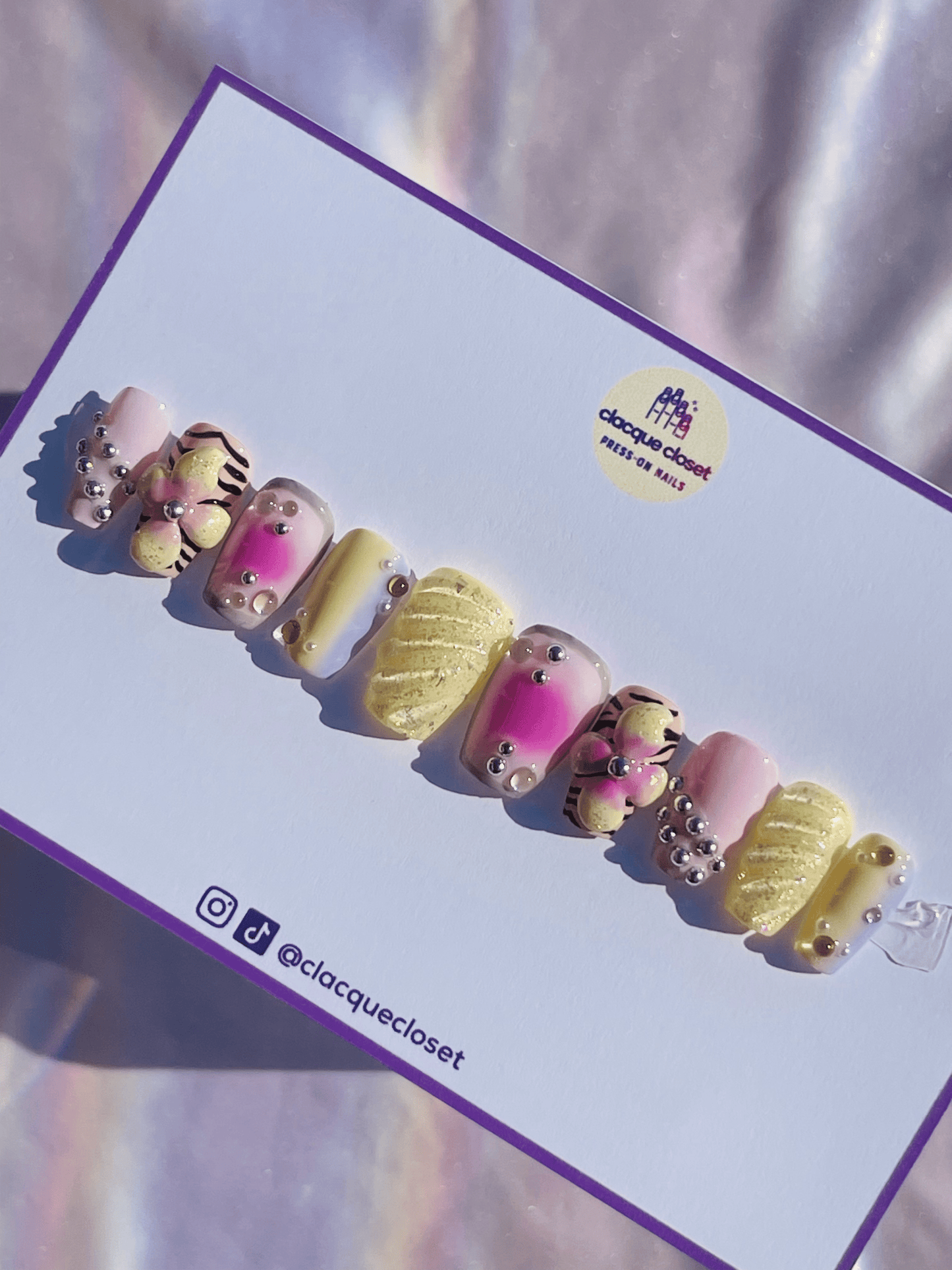 Press-on nails in pastel colors adorned with 3D flowers and charms, creating a delicate and whimsical design.