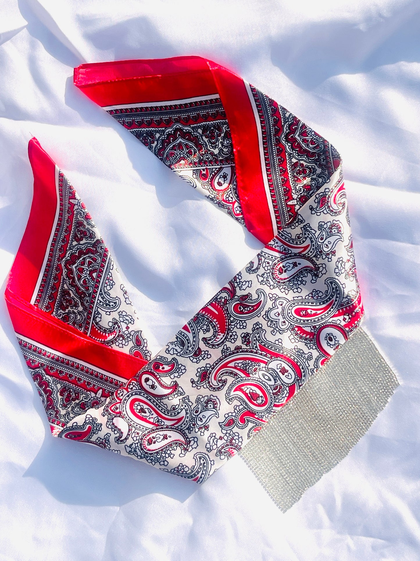 Crimson Nova red paisley bandana hair accessory with fringe detail, displayed flat to highlight the vibrant design and premium satin fabric.