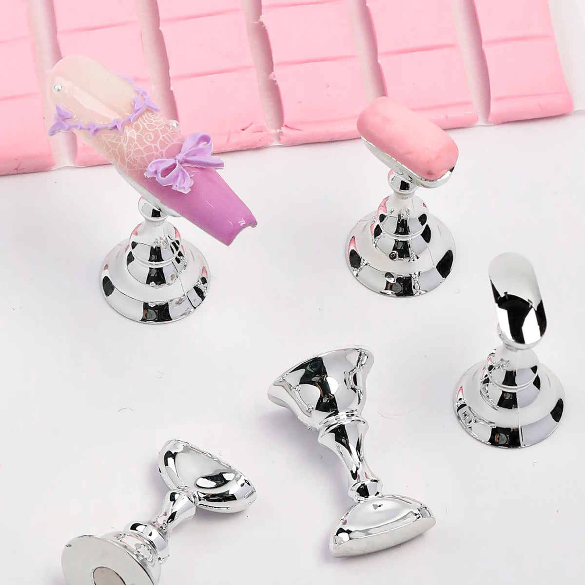Silver bell-shaped objects on a white surface with pink fabric in the background