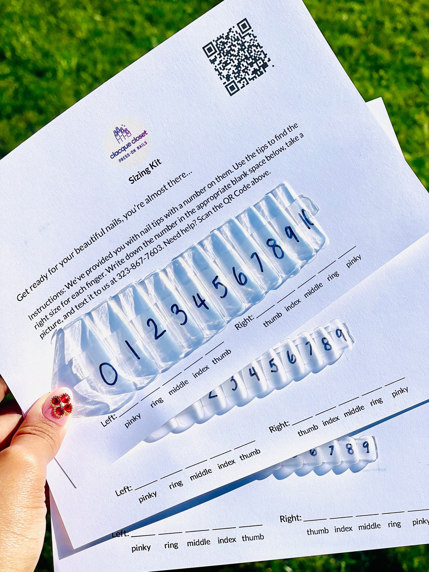 Photo of a physical nail size kit with a variety of nail tips laid out in order from smallest to largest, alongside a measuring tape for size comparison.