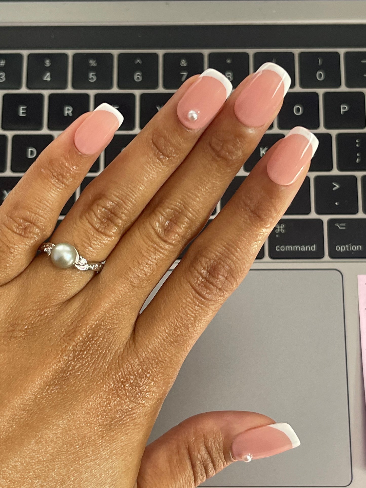 Classic French tip nails, characterized by their crisp white tips and natural pink bases, elegantly adorned with small pearl accents for a refined and timeless look.