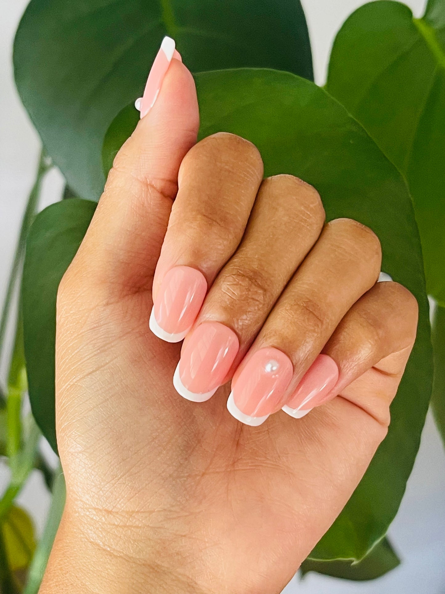 Classic French tip nails, characterized by their crisp white tips and natural pink bases, elegantly adorned with small pearl accents for a refined and timeless look.