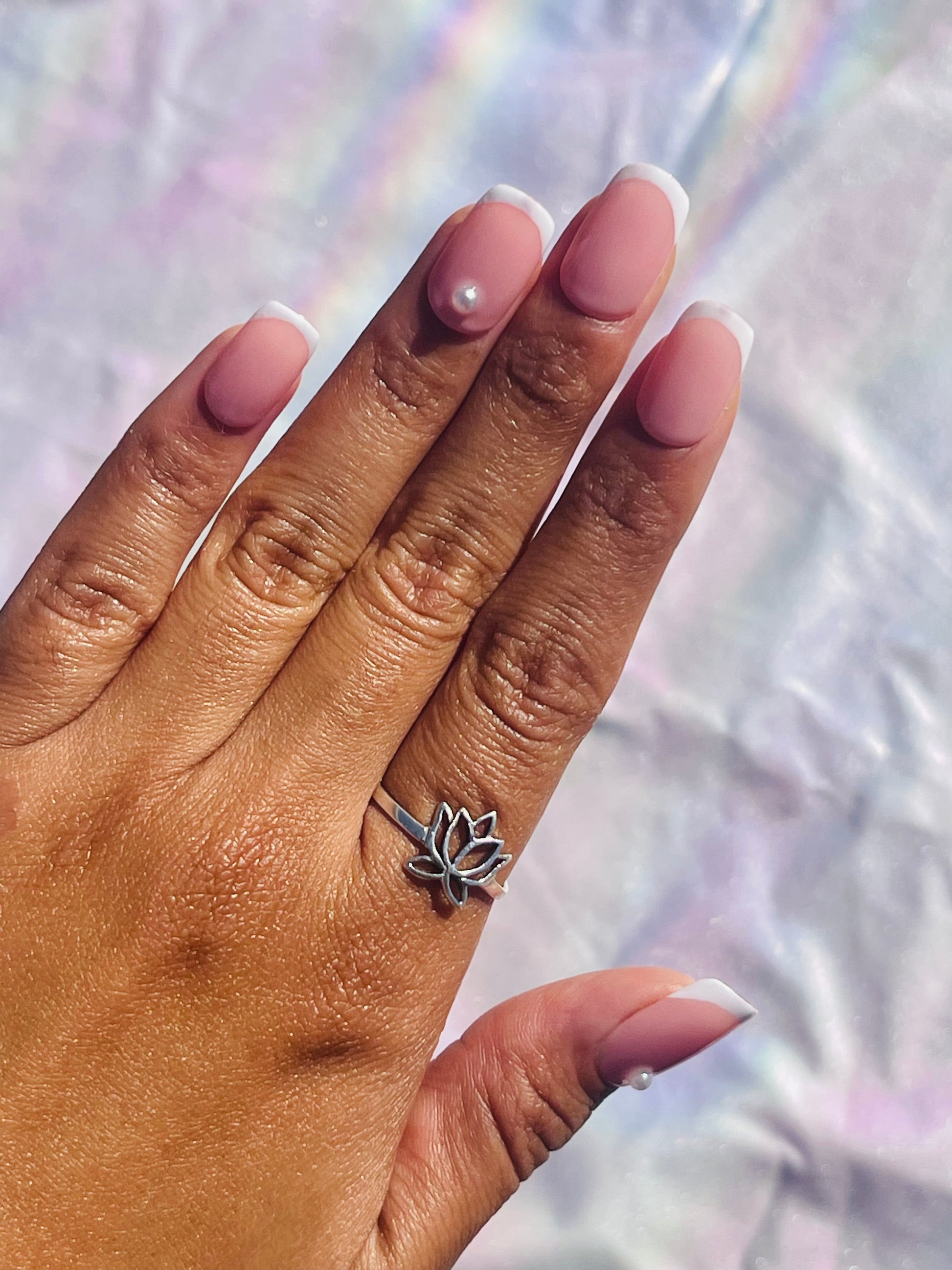 Classic French tip nails, characterized by their crisp white tips and natural pink bases, elegantly adorned with small pearl accents for a refined and timeless look.