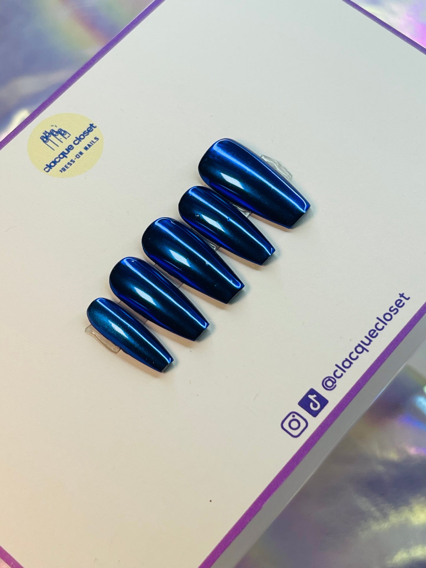 A set of press-on nails with a striking blue chrome finish, reflecting light to create a sleek and modern metallic look.