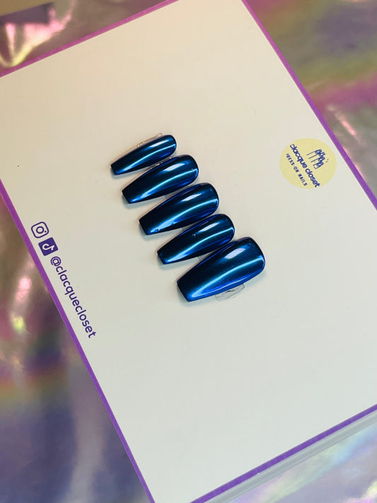 A set of press-on nails with a striking blue chrome finish, reflecting light to create a sleek and modern metallic look.