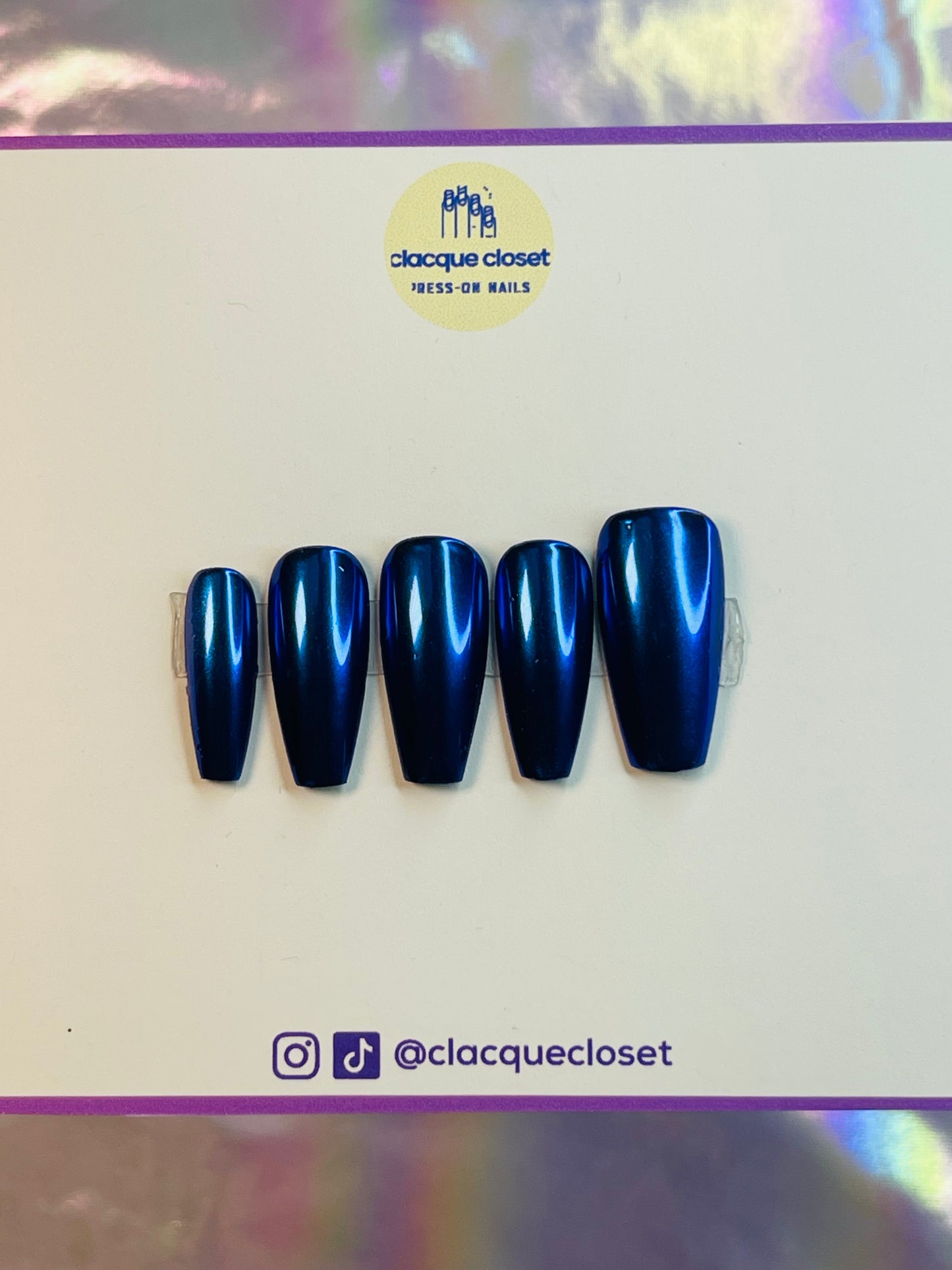 A set of press-on nails with a striking blue chrome finish, reflecting light to create a sleek and modern metallic look.