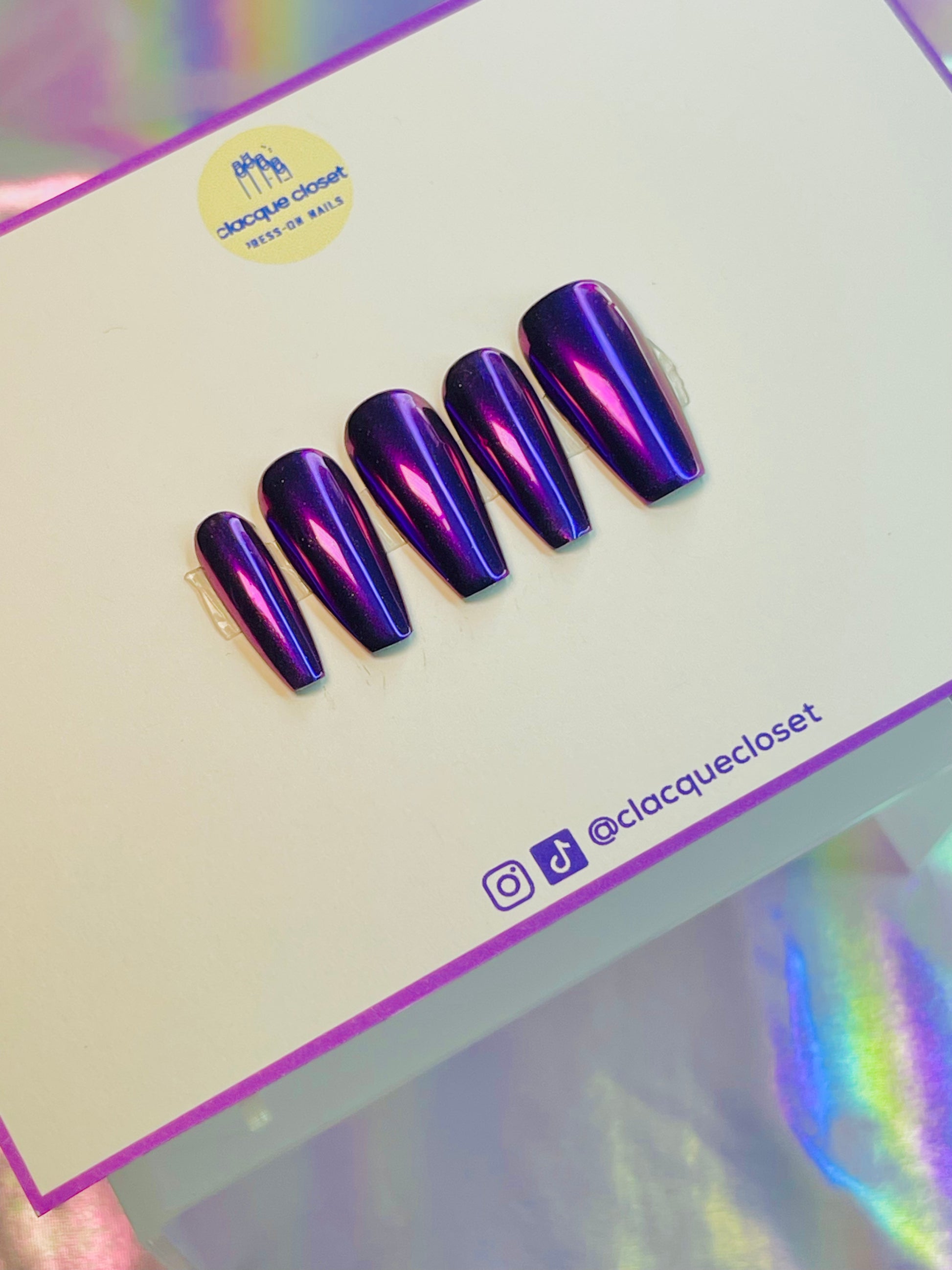 A set of press-on nails featuring a luminous purple chrome finish, giving off a vibrant, iridescent sheen that changes under different lighting conditions.