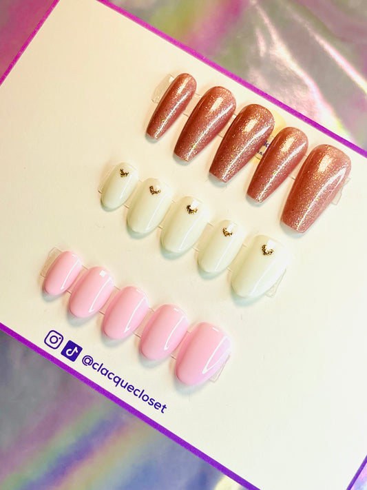 A bundle of three sets of nails, including glittery nude nails with a subtle sparkle, white nails adorned with glitter hearts for a whimsical touch, and a set named 'Tender Touch' featuring a soft, understated design.
