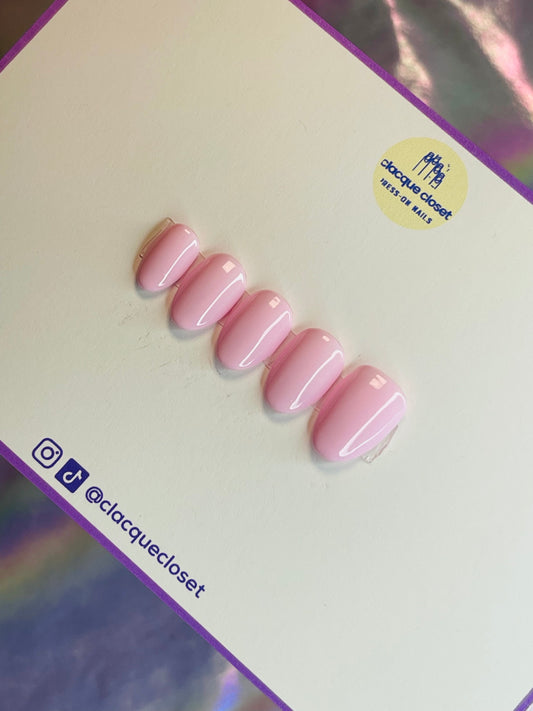 A set of press-on nails in a delicate baby pink shade, offering a soft and feminine appearance with a smooth, glossy finish.