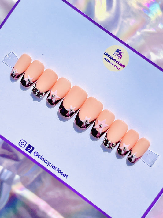 Medium-length coffin-shaped nails with a luxurious rose gold chrome French tip, embellished with pink stars and silver metal balls for a chic and elegant look.