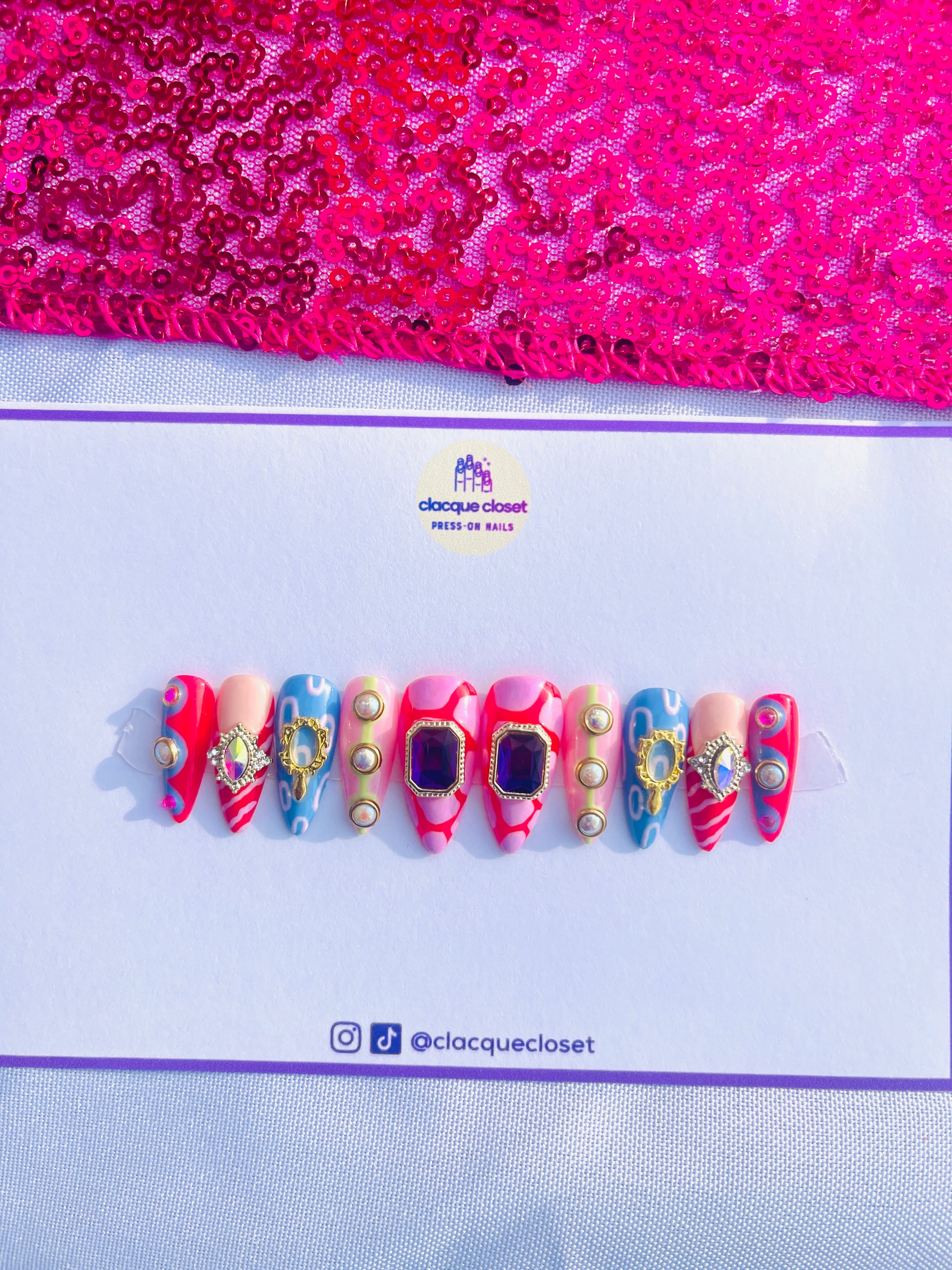 Medium-length stiletto nails featuring an extravagant set filled with various charms and abstract art designs, embodying a bold and artistic expression.