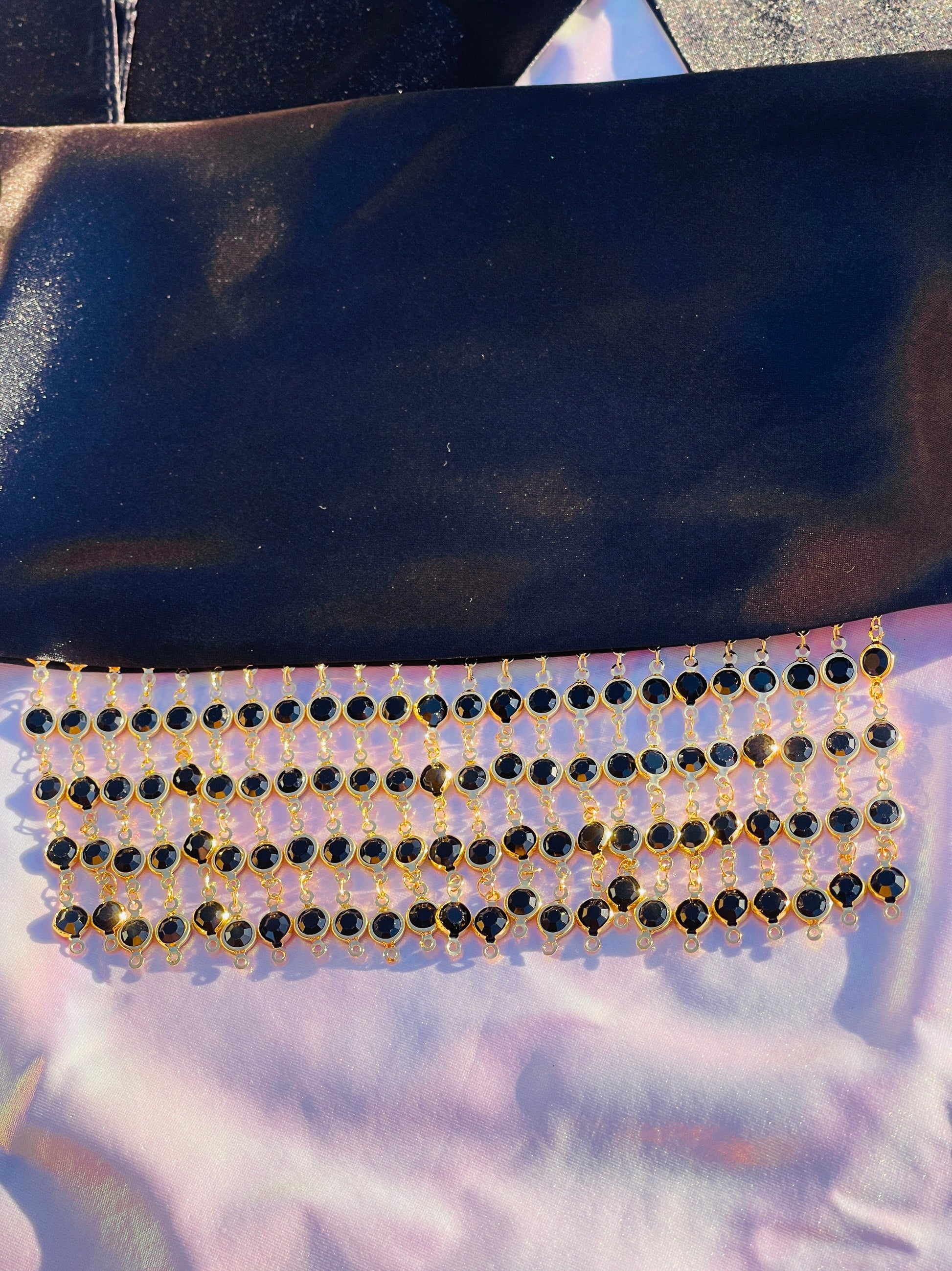 Close-up of the Kali black bandana bang with gold rhinestone fringe, lying flat.