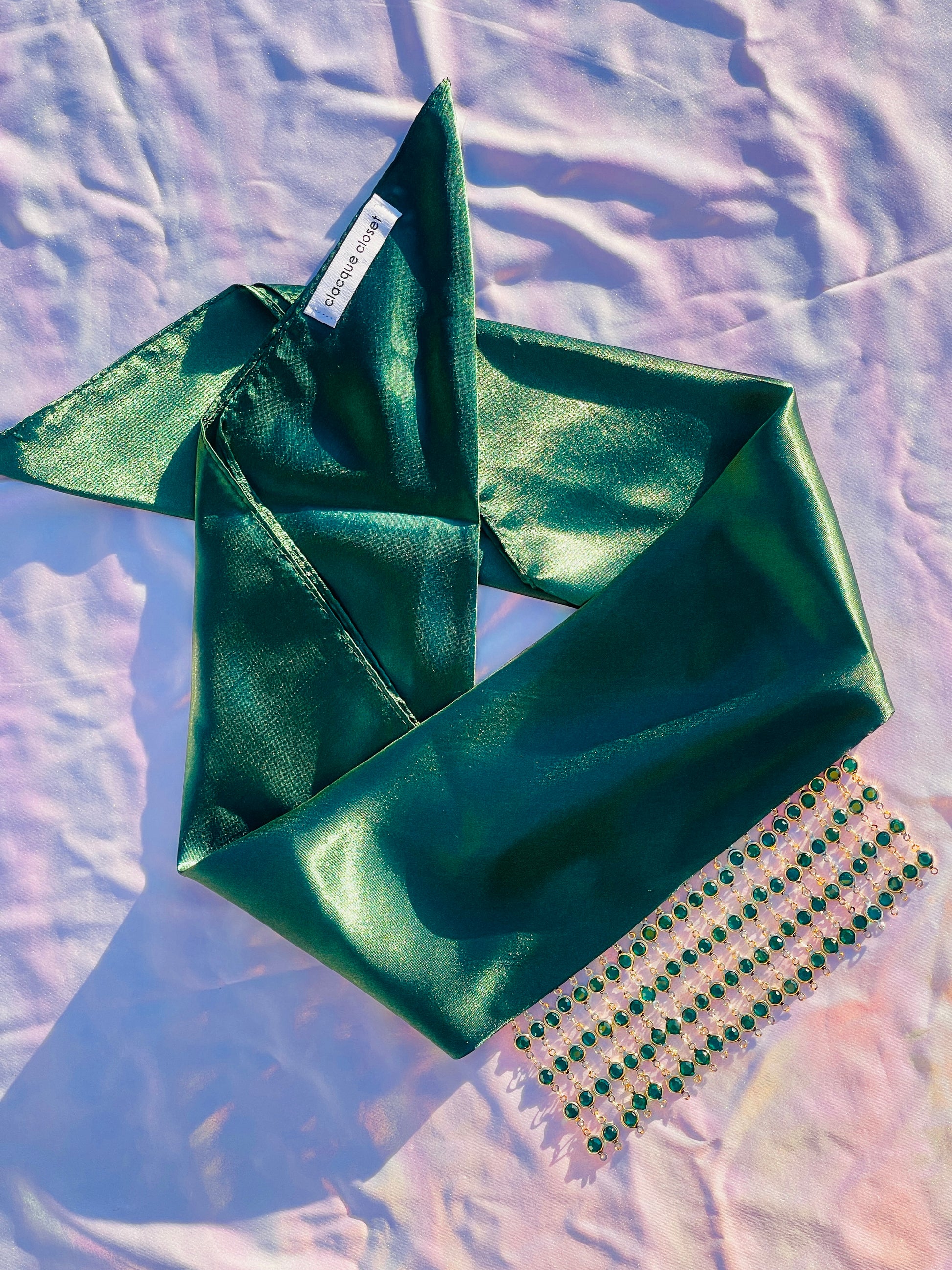 Close-up of the Demeter green bandana bang with gold rhinestone fringe, laid flat.