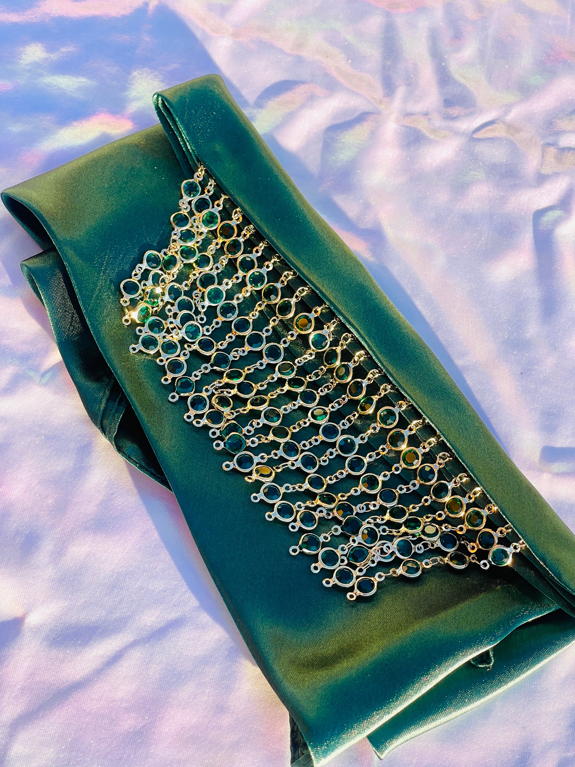 Close-up of the Demeter green bandana bang with gold rhinestone fringe, laid flat.