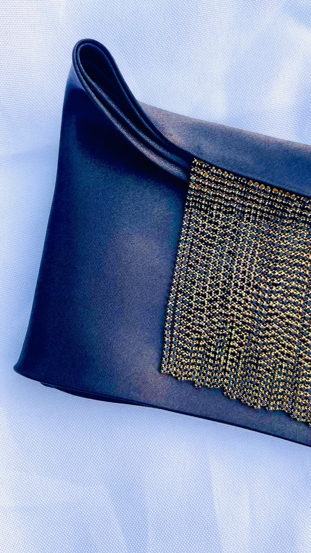 Video of Minerva black satin bandana bang with gold fringe laid flat.